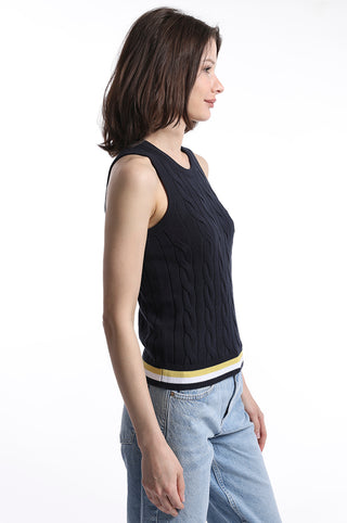 Model turned to the side wearing navy cable knit sweater tank top with yellow, white and navy stripe detail on bottom hem